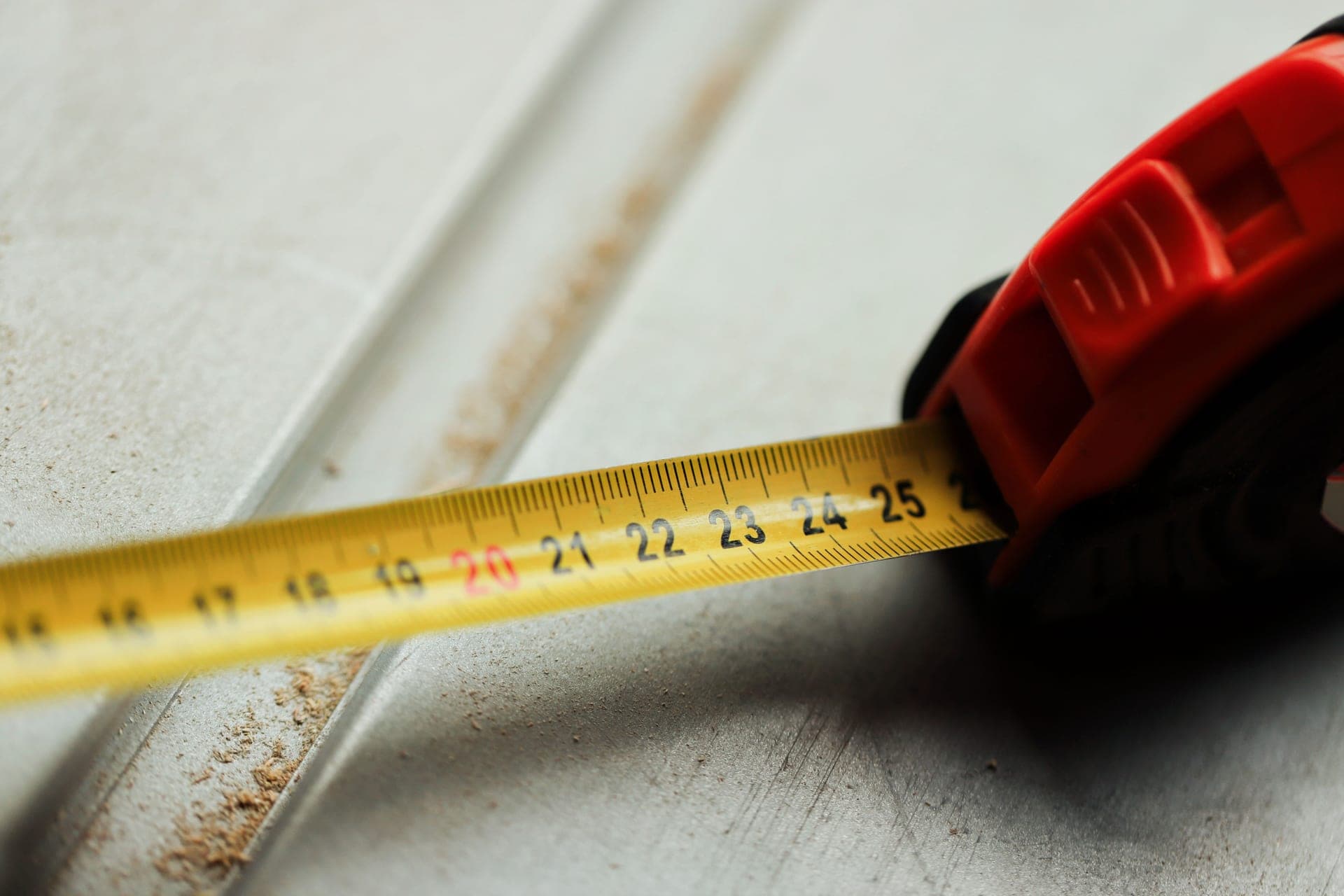 A steel tape measure held against the gap between a door and its threshold