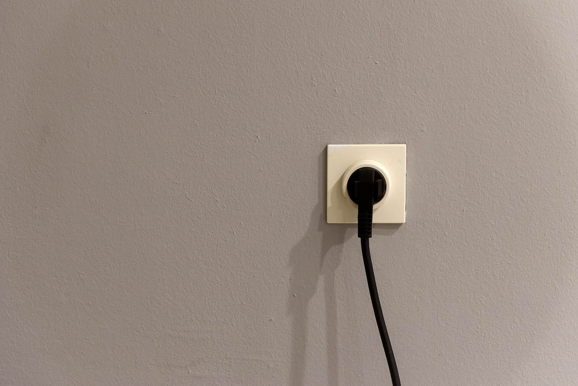 A wall outlet with its faceplate removed, showing the gap around the electrical box
