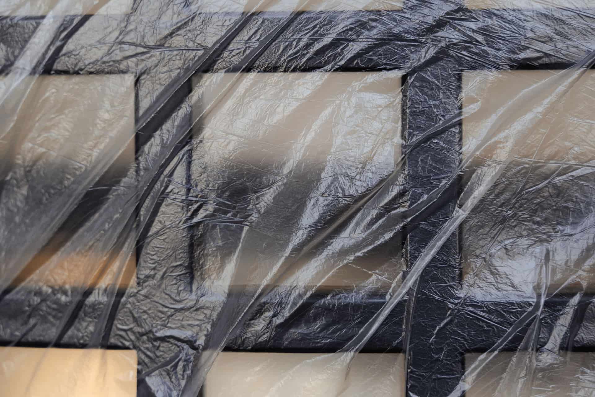 Clear shrink film stretched across an interior window frame with frost visible on the glass outside